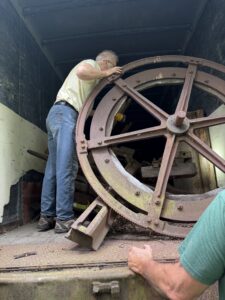 Man inspecting large, rusty industrial wheel.