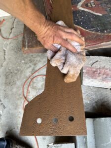 Hand cleaning rusty metal with cloth.
