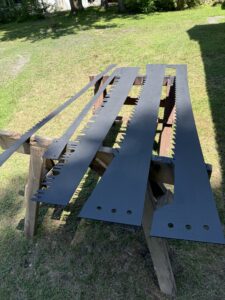 Metal blades drying on wooden sawhorses outside.