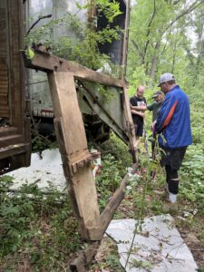 People inspecting abandoned vehicle in forest.
