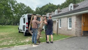 Two people unloading large object from van.