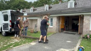 Men moving wooden beam into building.