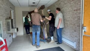 People moving large object in hallway.