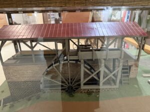 Model of a waterwheel under red roof.