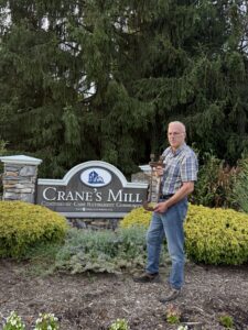 Man standing by Crane's Mill sign.