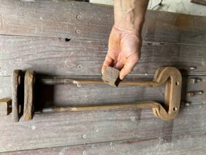 Hand holding rusty metal cube and clamp.