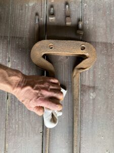 Hand cleaning rusty metal tool on table.