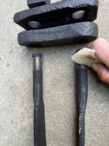 Hand holding a metal component near bolts.